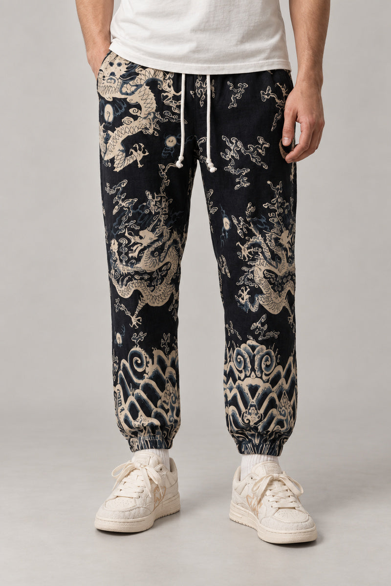 All Over Dragon Print Joggers 'Watatsumi' – black joggers with all over cream dragon and wave print, Japanese streetwear pants, front view on model