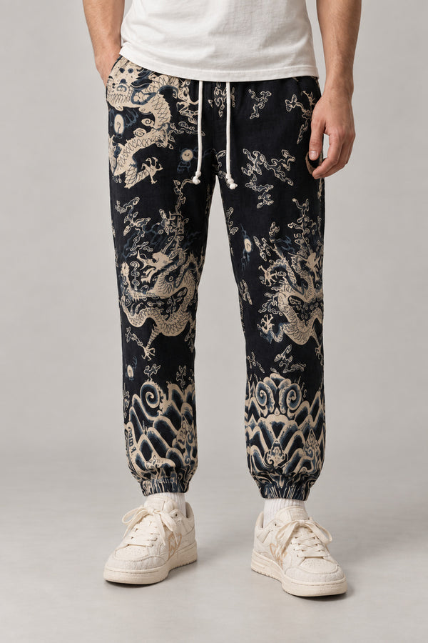 All Over Dragon Print Joggers 'Watatsumi' – black joggers with all over cream dragon and wave print, Japanese streetwear pants, front view on model