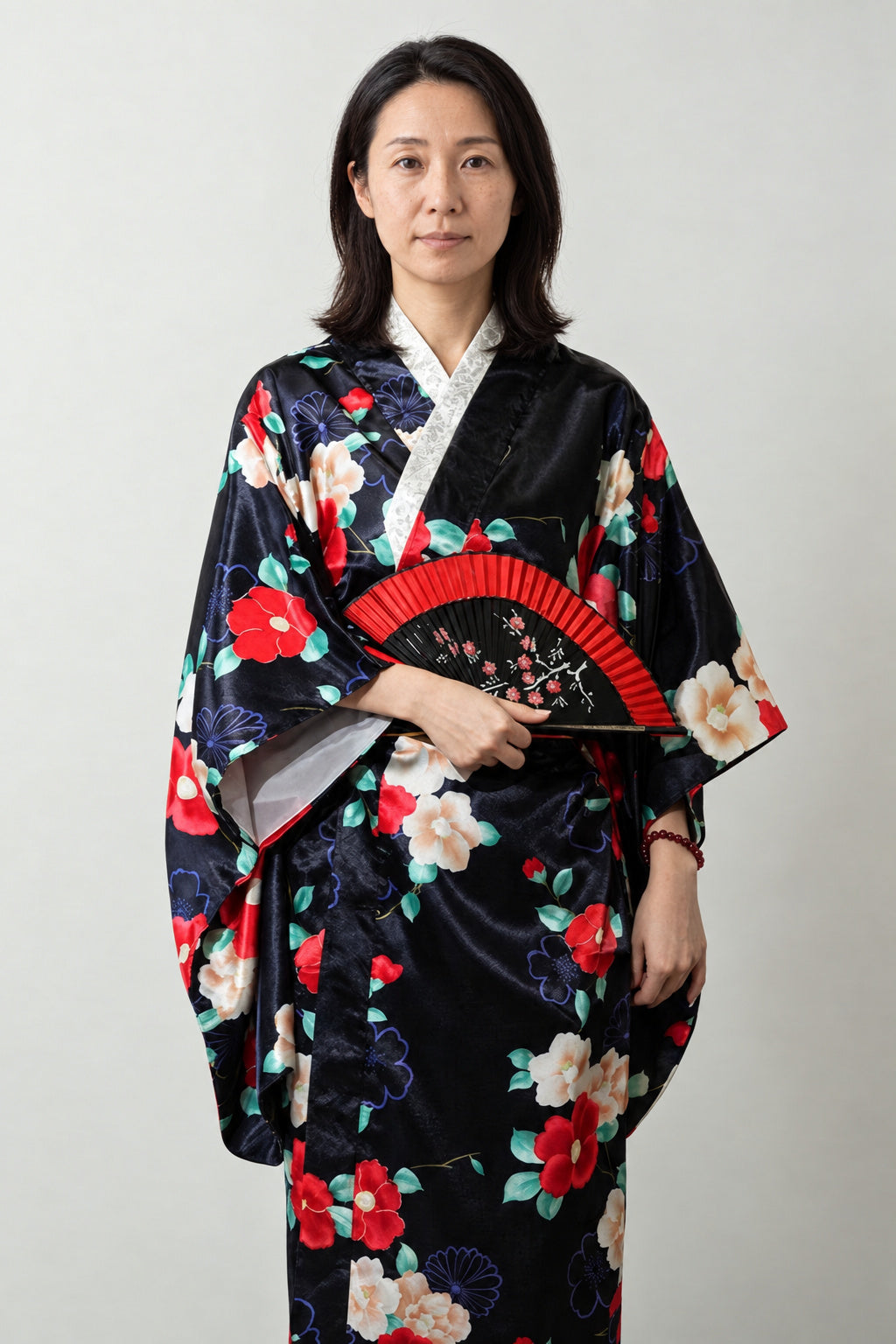 Black Camellia Kimono Robe 'Kantsubaki' – black women's kimono robe with red camellia flower print and folding fan, long Japanese satin-look kimono, front view on model