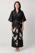 Black Crane Long Japanese Robe 'Tsuruyoru' – black women's long satin-look kimono robe with pink crane print and tie belt, Japanese dressing gown, front view on model