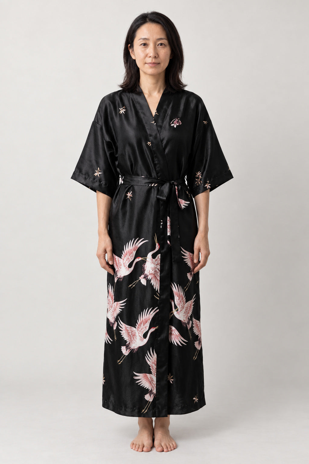 Black Crane Long Japanese Robe 'Tsuruyoru' – black women's long satin-look kimono robe with pink crane print and tie belt, Japanese dressing gown, front view on model