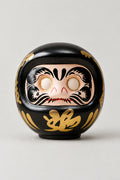 Black Daruma Doll 'Kurodaruma' – black matte ceramic daruma doll with blank eyes to paint and a gold character on the belly, Japanese wishing doll, studio view