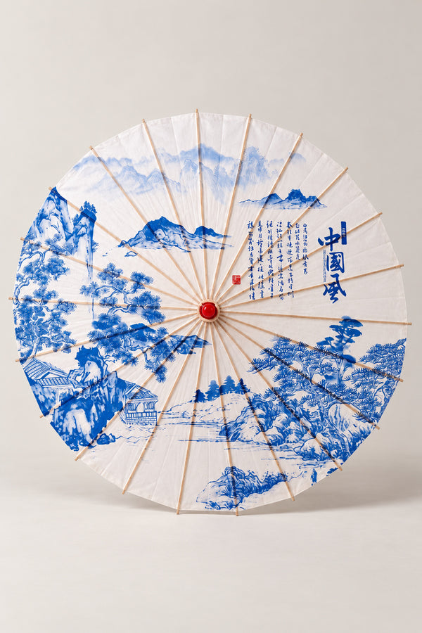 Blue Landscape Paper Parasol 'Sansui' – white parasol printed with a blue ink mountain landscape, pines and a calligraphy column, Japanese wagasa parasol with wooden frame and paper-effect canopy, open, studio view