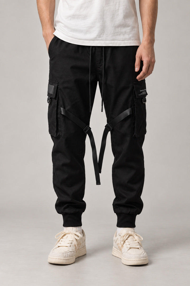 Buckle Strap Techwear Joggers 'Kusari' – black techwear joggers with buckle straps and cargo pockets, Japanese streetwear pants, front view on model