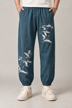Crane Flock Embroidered Pants 'Tsurumure' – teal crane embroidered joggers, side view on model