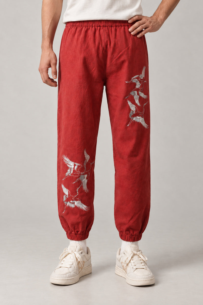 Crane Flock Embroidered Pants 'Tsurumure' – red version of the crane flock embroidered joggers, front view on model
