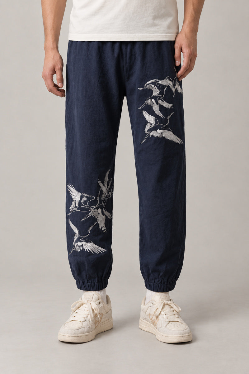 Crane Flock Embroidered Pants 'Tsurumure' – navy crane flock embroidered joggers, front view on model