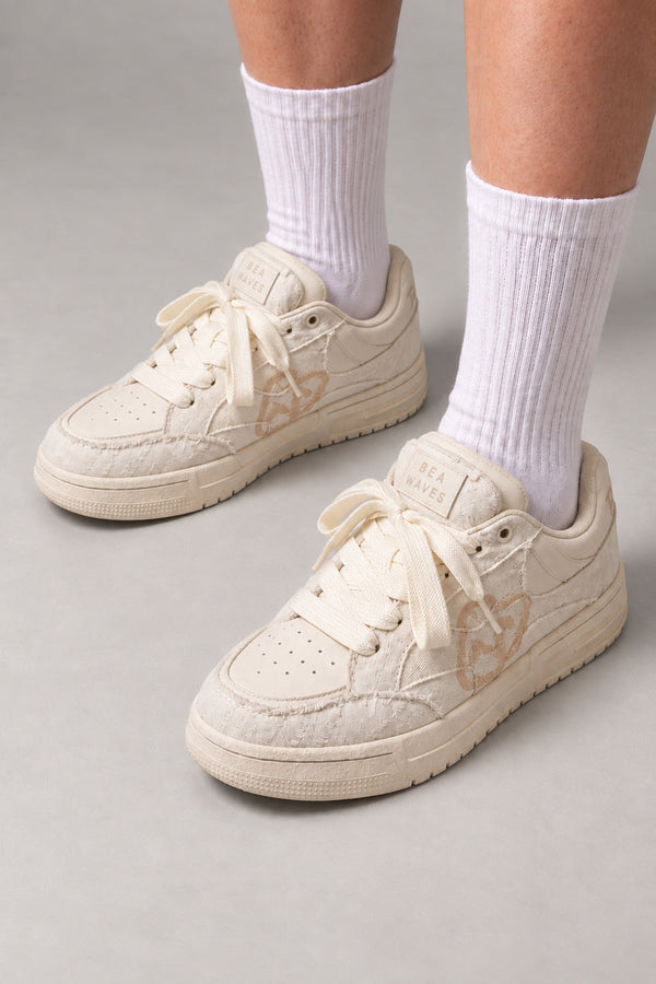 Cream Frayed Low Top Sneakers 'Nyuhaku' – cream frayed panel low top sneakers with stitched heart, Japanese streetwear sneakers worn with white socks, on model