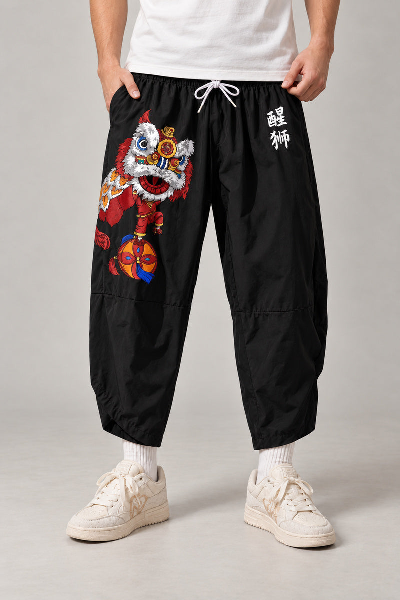 Cropped Japanese Print Pants 'Jukkei' – black cropped pants with red shishi lion and kanji print, front view on model