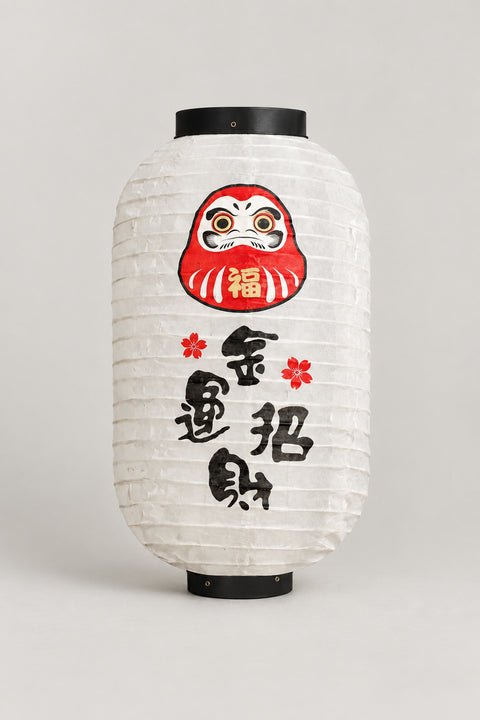 Daruma Chochin Paper Lantern 'Fukuakari' – white barrel chochin paper lantern with black rims printed with a red daruma face and brushed kanji, Japanese izakaya lantern, studio view