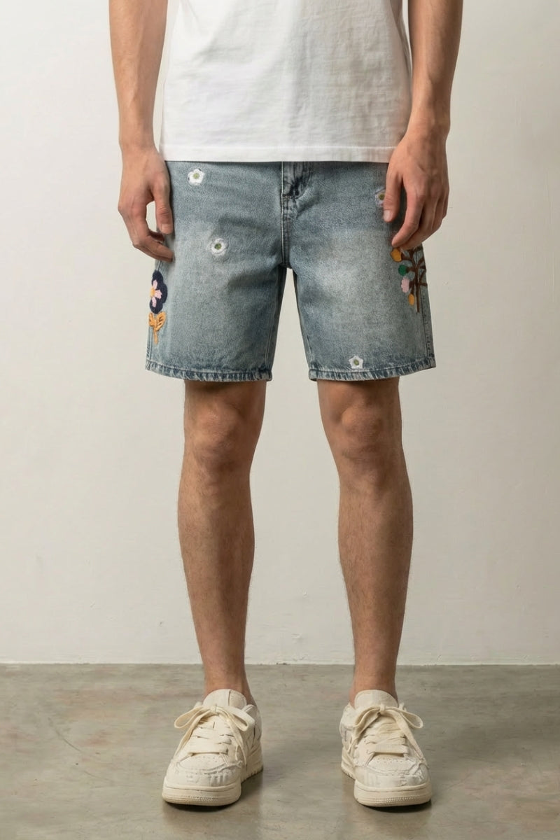 Flower Embroidered Denim Shorts 'Nohana' – light blue denim shorts with embroidered flowers and daisies, front view on model, studio