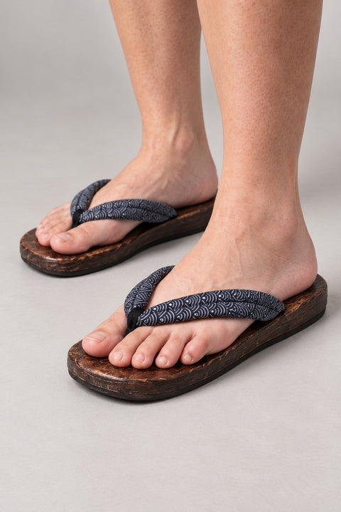 Japanese Flip Flops 'Karakoro' – wooden flip flops with navy wave print padded thong, flat Japanese wooden sandals worn barefoot, front view on model