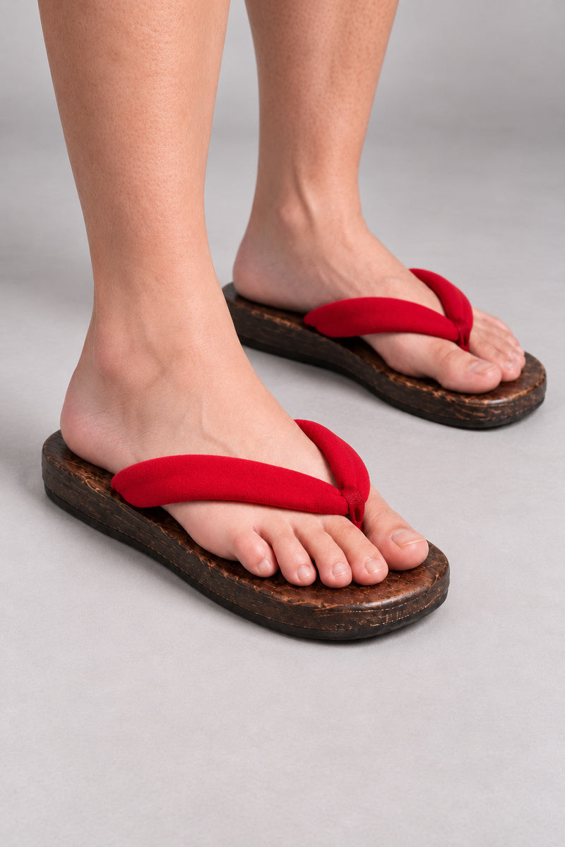 Japanese Flip Flops 'Karakoro' – wooden flip flops with plain red padded thong, flat Japanese wooden sandals worn barefoot, front view on model