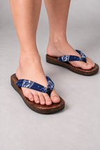 Japanese Flip Flops 'Karakoro' – wooden flip flops with navy and blue print thong, flat Japanese wooden sandals worn barefoot, front view on model