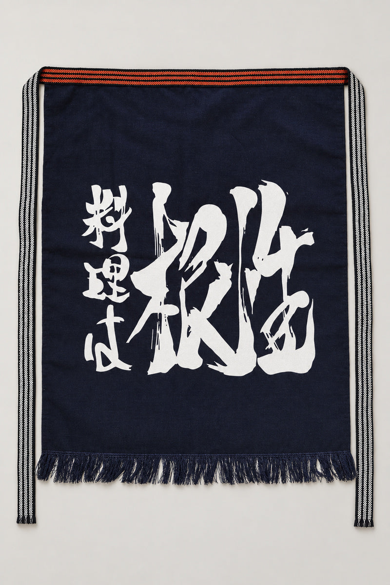 Maekake – indigo maekake apron printed with bold brushed kanji in a diagonal, traditional Japanese sake brewery waist apron with fringed hem, studio view