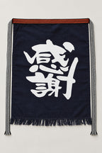 Maekake – indigo maekake apron printed with the bold kanji for gratitude, traditional Japanese sake brewery waist apron with fringed hem, studio view