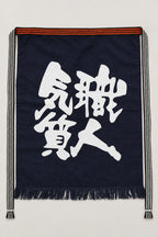 Maekake – indigo maekake apron printed with the kanji for craftsman spirit, traditional Japanese sake brewery waist apron with fringed hem, studio view