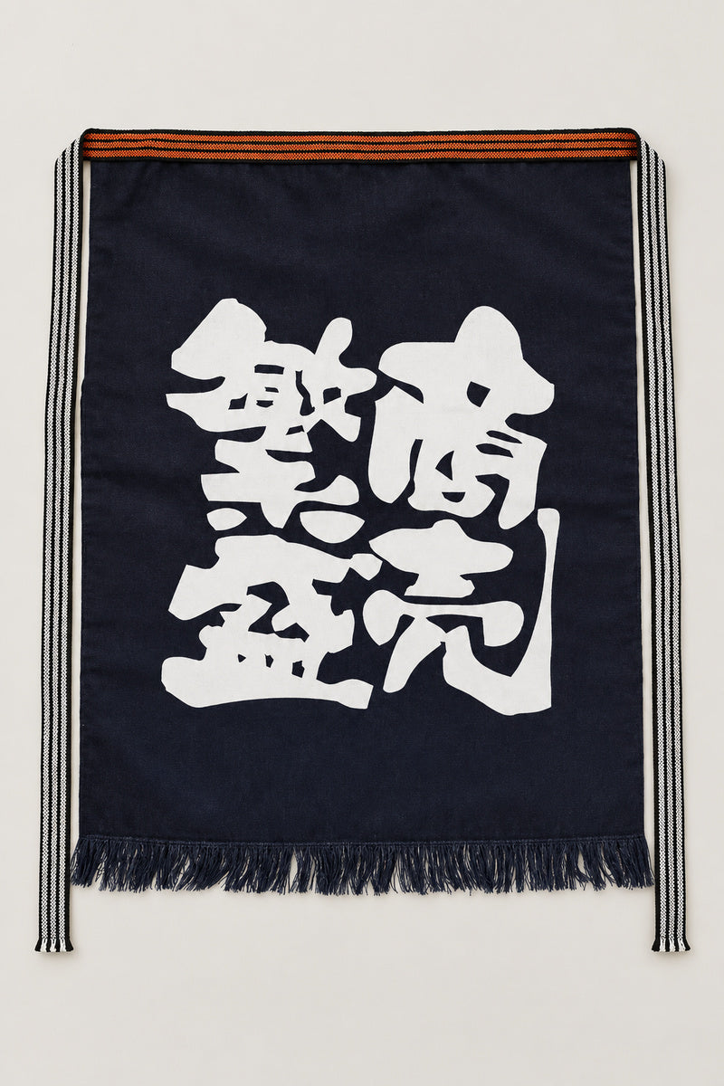 Maekake – indigo maekake apron printed with the kanji for prosperous business, traditional Japanese sake brewery waist apron with fringed hem, studio view