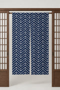 Navy Chevron Noren 'Yamagata' – navy noren with white chevron pattern, split Japanese noren door curtain hung on a rod between sliding screens, studio view