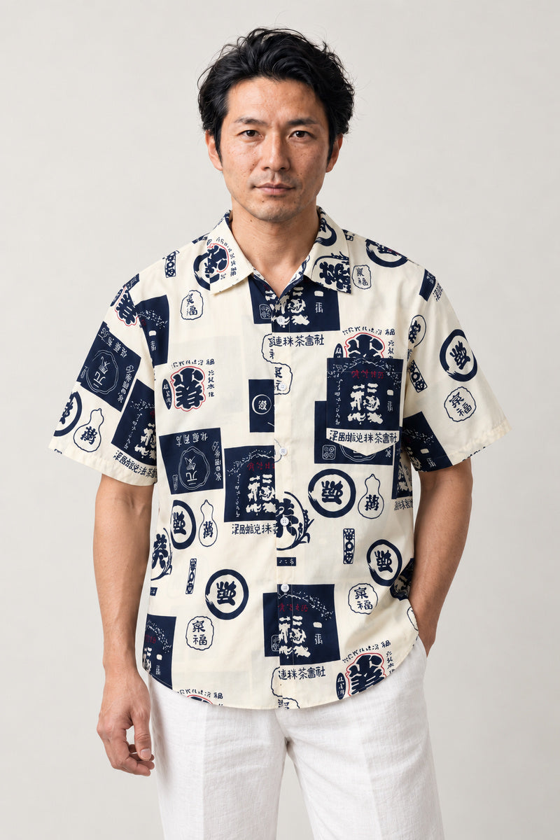 Navy Kanji Label Shirt 'Yago' – cream short sleeve shirt with navy kanji label and crest print, Japanese streetwear camp collar shirt, front view on model