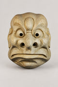 Okinawa Theater Mask 'Ryukyu' – unpainted wooden Okinawan style mask with round eyes, bulbous nose and downturned mouth, hand carved wooden Japanese mask for the wall, studio view