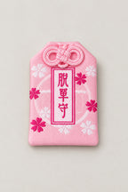 Omamori – pink brocade omamori amulet with kanji for victory and cherry blossom, Japanese lucky charm, studio view