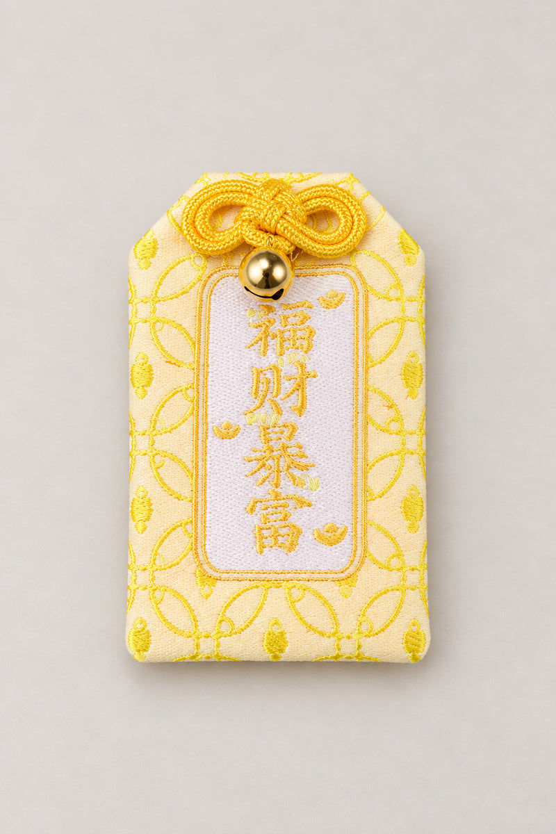 Omamori – yellow brocade omamori amulet with kanji for wealth and gold pattern, Japanese lucky charm, studio view