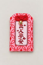 Omamori – red brocade omamori amulet with kanji for family safety and pink pattern, Japanese lucky charm, studio view