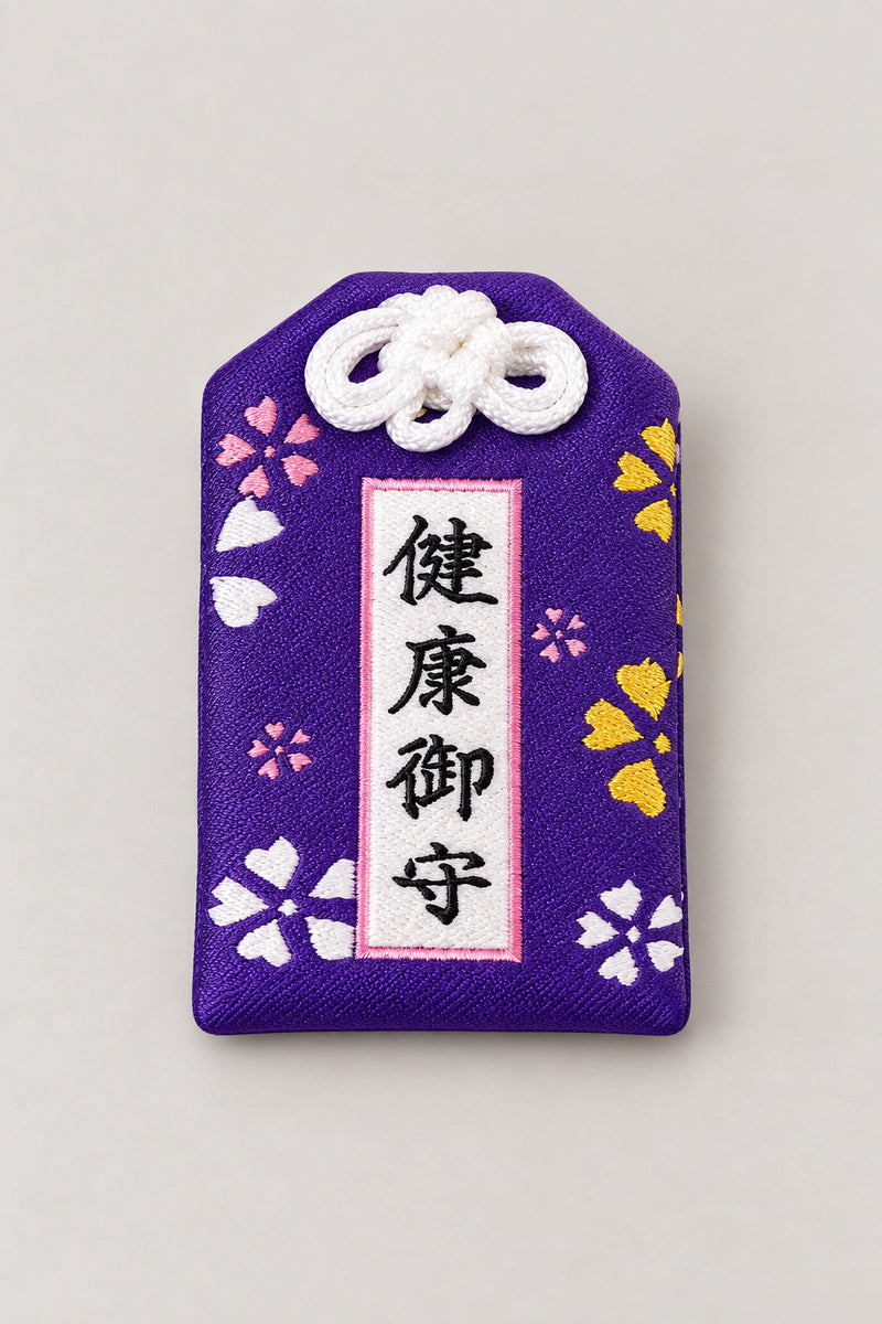 Omamori – purple brocade omamori amulet with gold kanji for health and cherry blossom, Japanese lucky charm, studio view