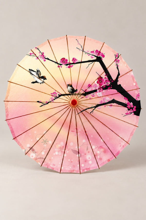 Peach Blossom Wagasa Parasol 'Momozono' – pink and yellow parasol printed with a black plum branch, blossom and two birds, Japanese wagasa parasol with wooden frame and paper-effect canopy, open, studio view