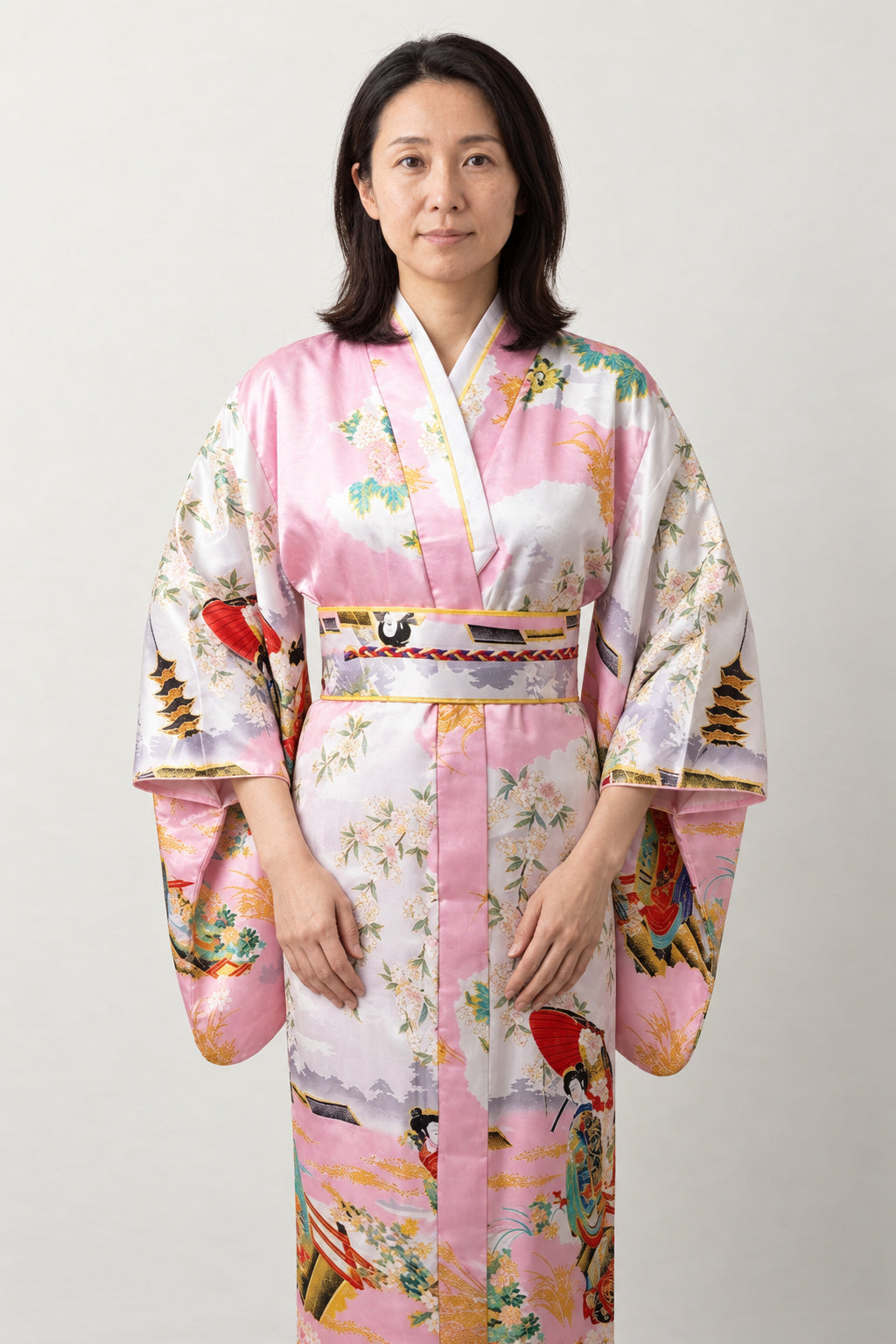 Pink Satin Kimono 'Maiogi' – pale pink women's satin-look kimono robe with peacock and pagoda print and red obi, long Japanese kimono, front view on model