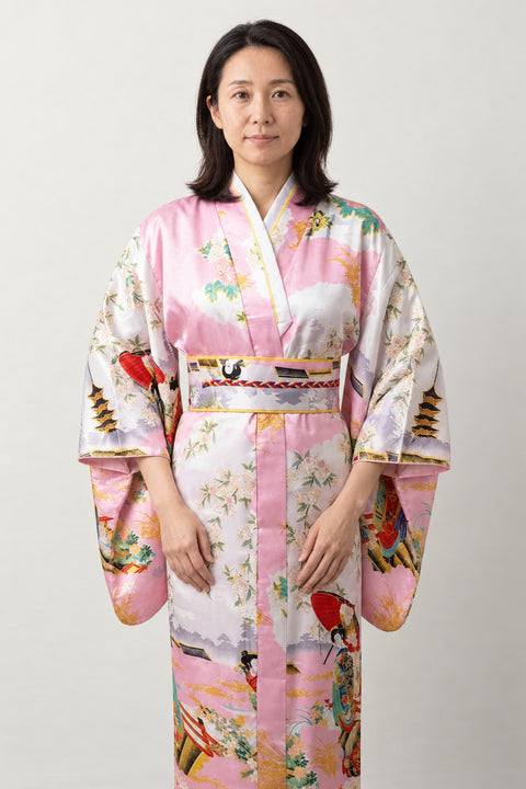 Pink Satin Kimono 'Maiogi' – pale pink women's satin-look kimono robe with peacock and pagoda print and red obi, long Japanese kimono, front view on model