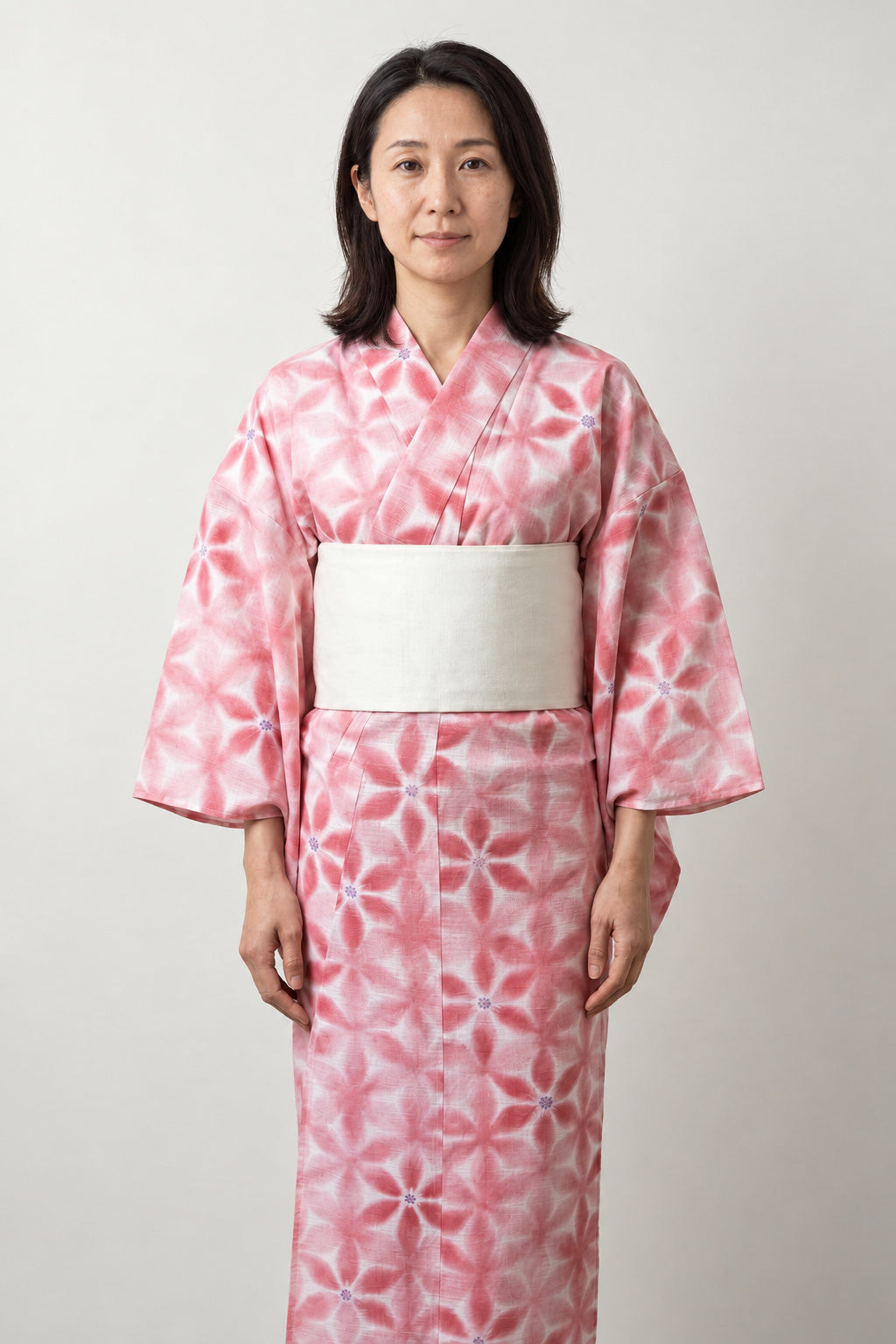 Pink Yukata Kimono 'Momoiro' – pink women's yukata with white floral print and cream obi belt, traditional Japanese summer kimono, front view on model