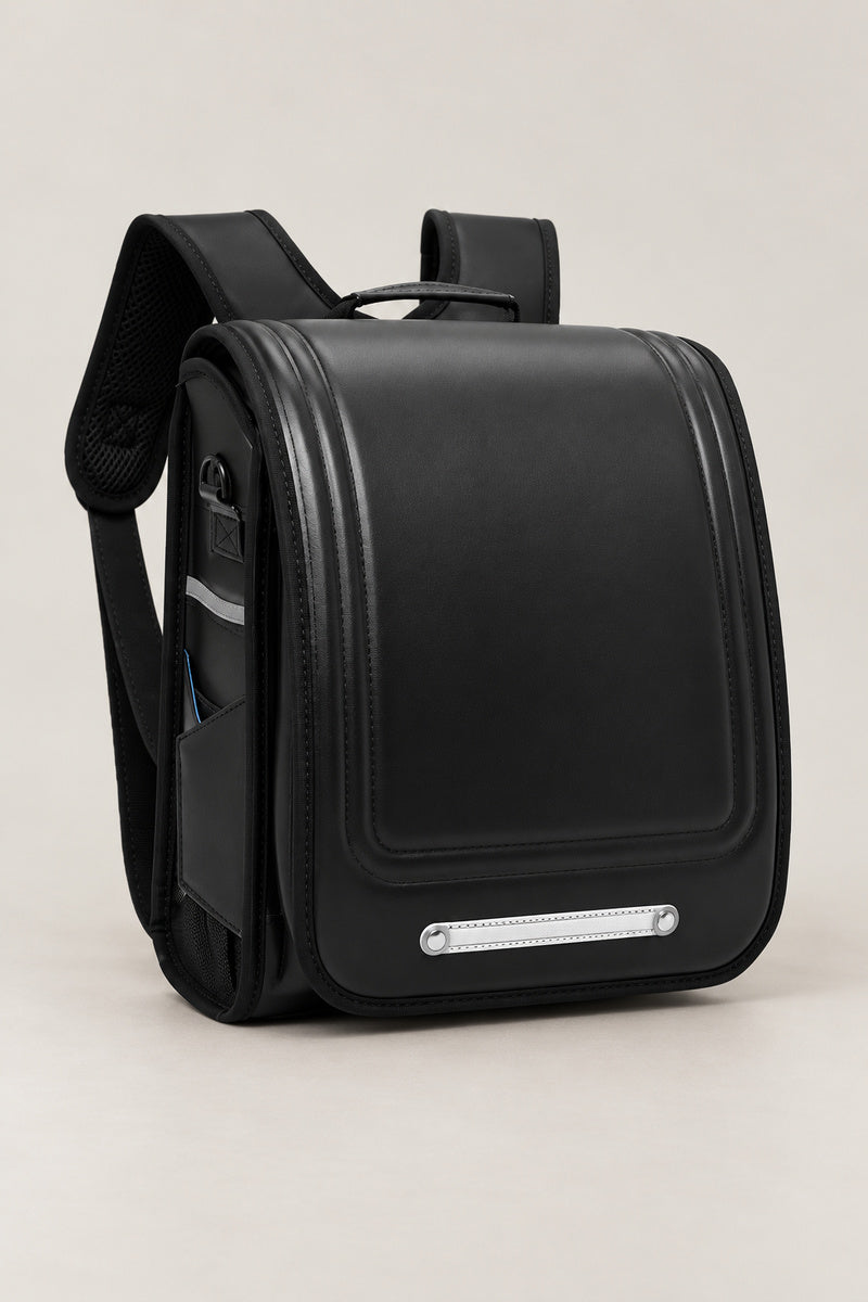 Randoseru – black randoseru Japanese school backpack with long flap and metal plate, front view, studio