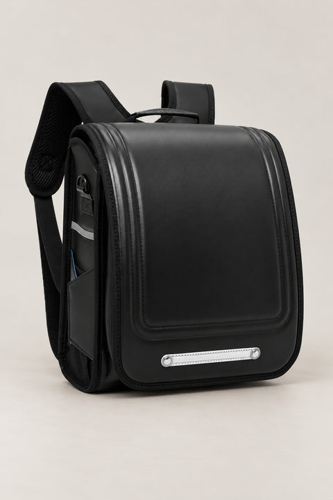 Randoseru – black randoseru Japanese school backpack with long flap and metal plate, front view, studio