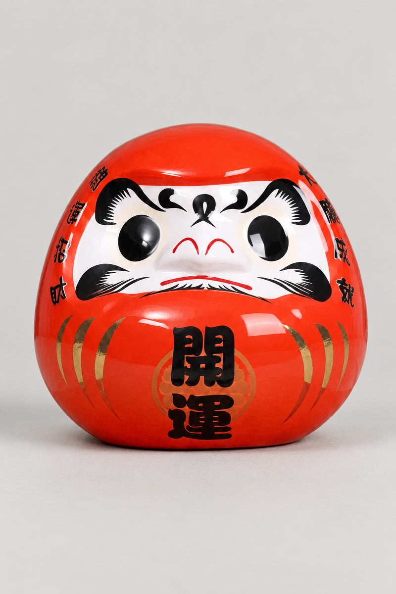 Shogun Red Daruma Figurine 'Taisho' – red glossy ceramic daruma doll with both eyes painted, gold streaks and the kanji for opening luck on the belly, Japanese good luck doll, studio view