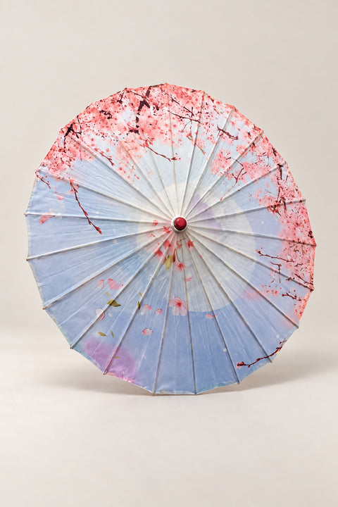 Sky Blue Sakura Wagasa Umbrella 'Harusora' – sky blue parasol printed with pink cherry blossom over a pale moon, Japanese wagasa parasol with wooden frame and paper-effect canopy, open, studio view
