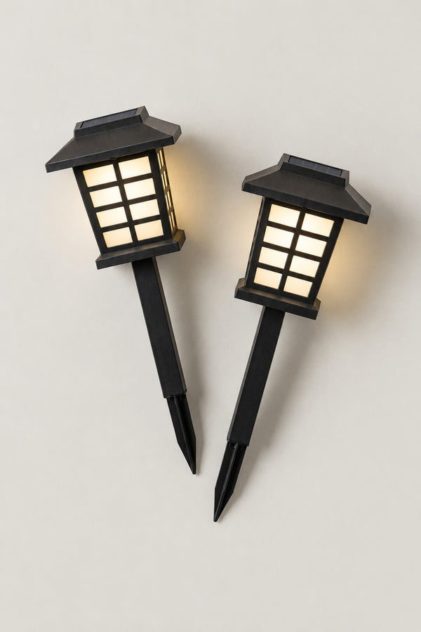 Solar Japanese Garden Lanterns 'Michiakari' – set of two black solar garden lanterns on stakes shaped as Japanese stone lanterns with latticed windows, lit, studio view