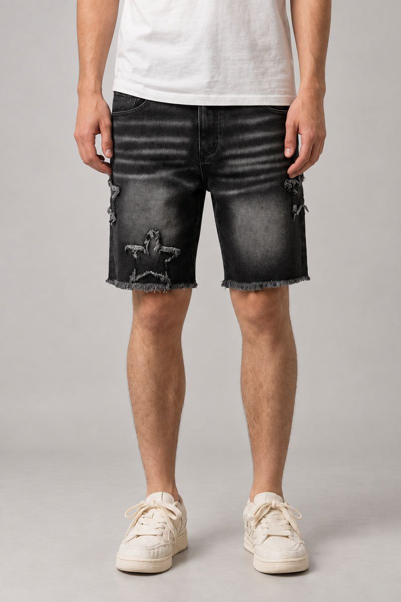 Star Print Black Denim Shorts 'Hoshikuzu' – black washed denim shorts with frayed star patches and raw hem, Japanese streetwear shorts, front view on model