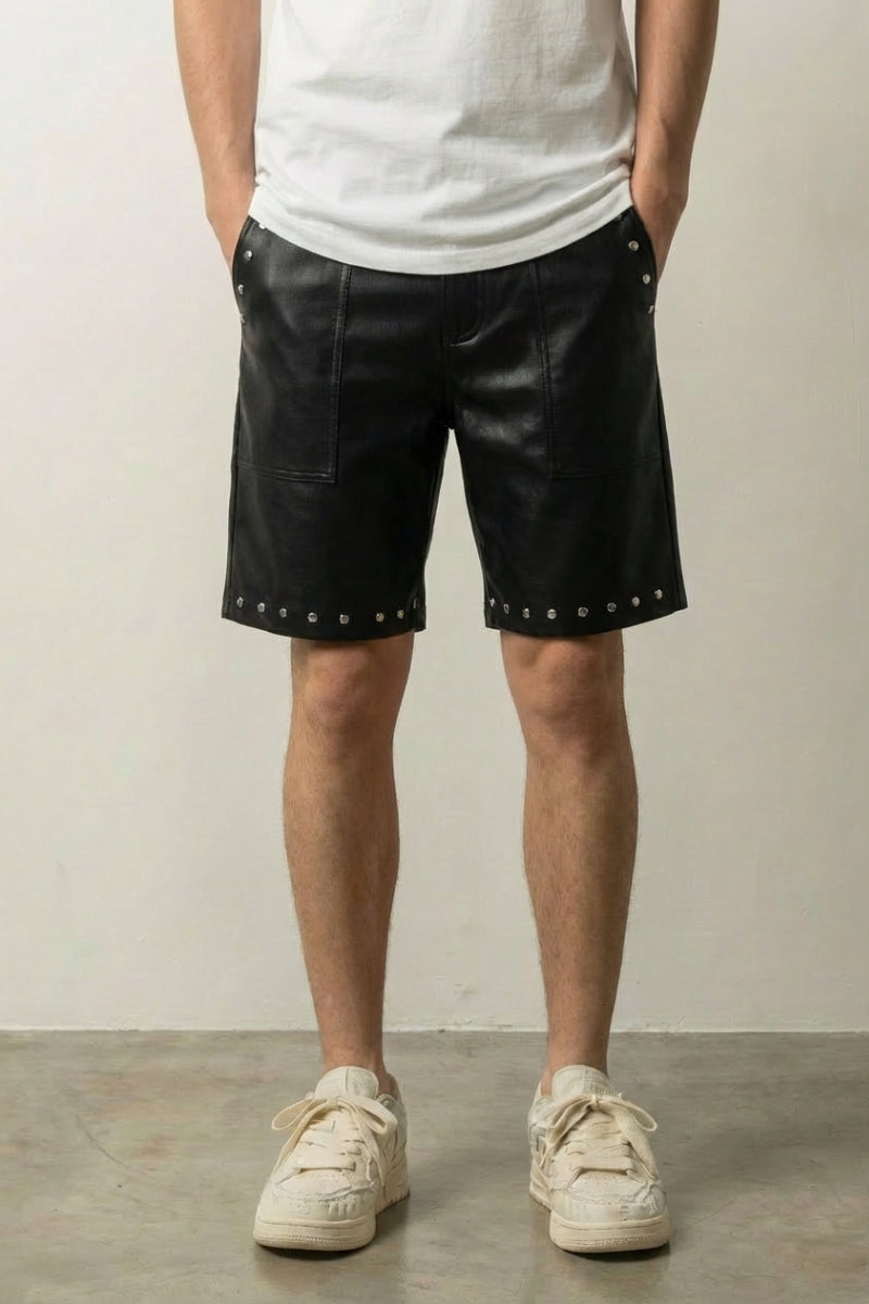 Studded Faux Leather Shorts 'Byo' – black studded faux leather shorts with silver studs at the hem, front view on model, studio