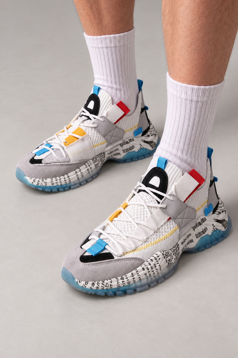 Text Print Sole Sneakers 'Sumiji' – white and grey sneakers with text print sole and blue, red and yellow tabs, Japanese streetwear sneakers worn with white socks, on model