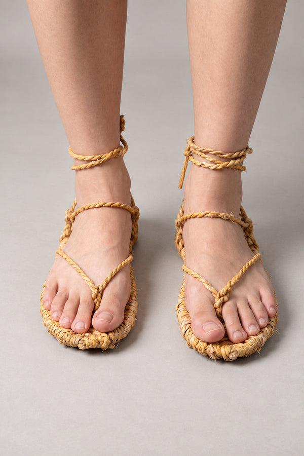 Waraji Sandals – woven straw waraji sandals with rope cords tied round the ankle, traditional Japanese straw footwear, worn barefoot, front view on model