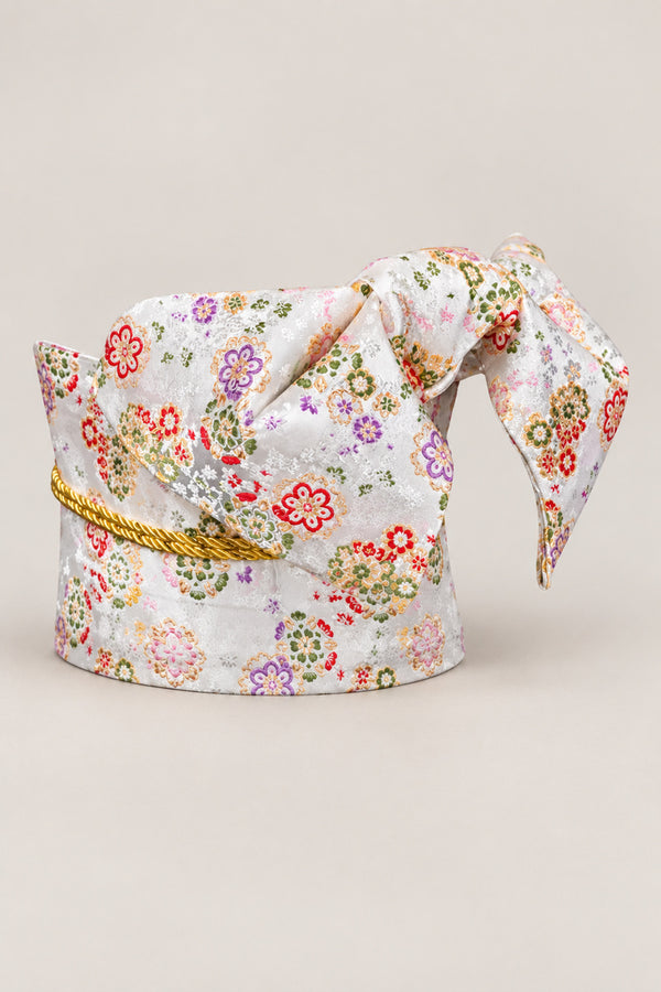 White Floral Brocade Obi 'Kohana' – white brocade obi with small red, purple and green flowers and gold cord, wide pre-tied brocade obi belt with sewn bow for women's kimono or yukata, studio view