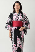 Women's Black Sakura Kimono 'Yaezakura' – black women's kimono with pink cherry blossom print and red obi belt, traditional Japanese yukata, front view on model