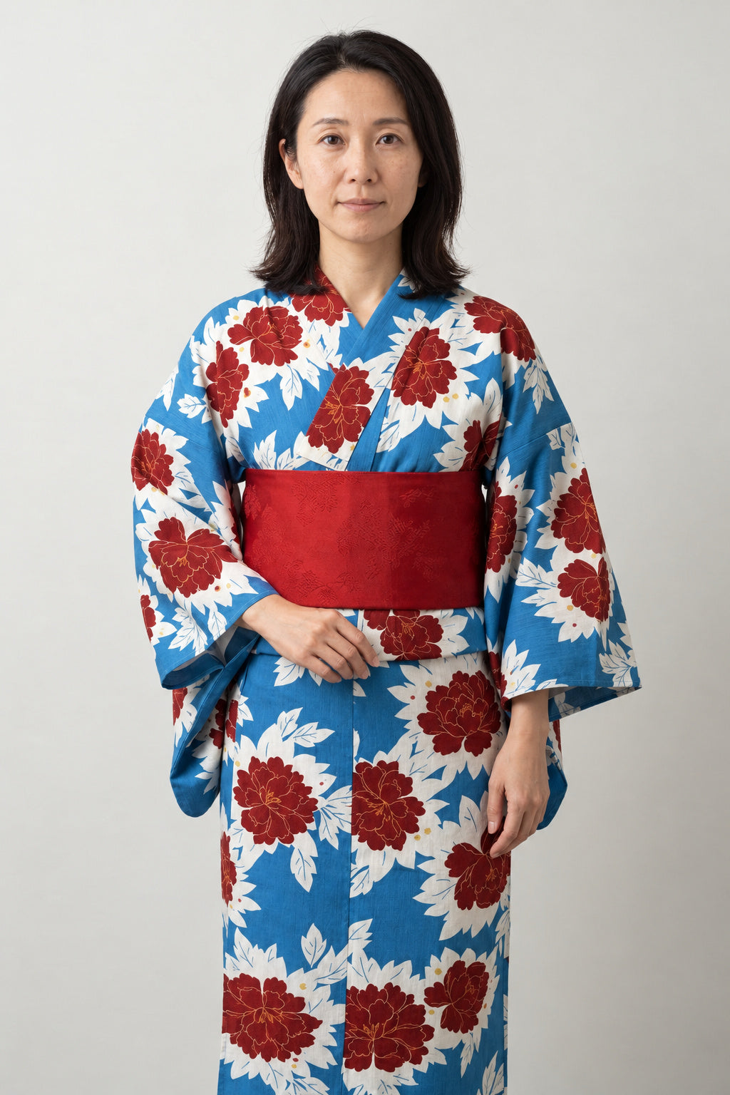 Women's Blue Peony Yukata 'Hibotan' – white women's yukata with blue and red peony print and red obi belt, traditional Japanese summer kimono, front view on model