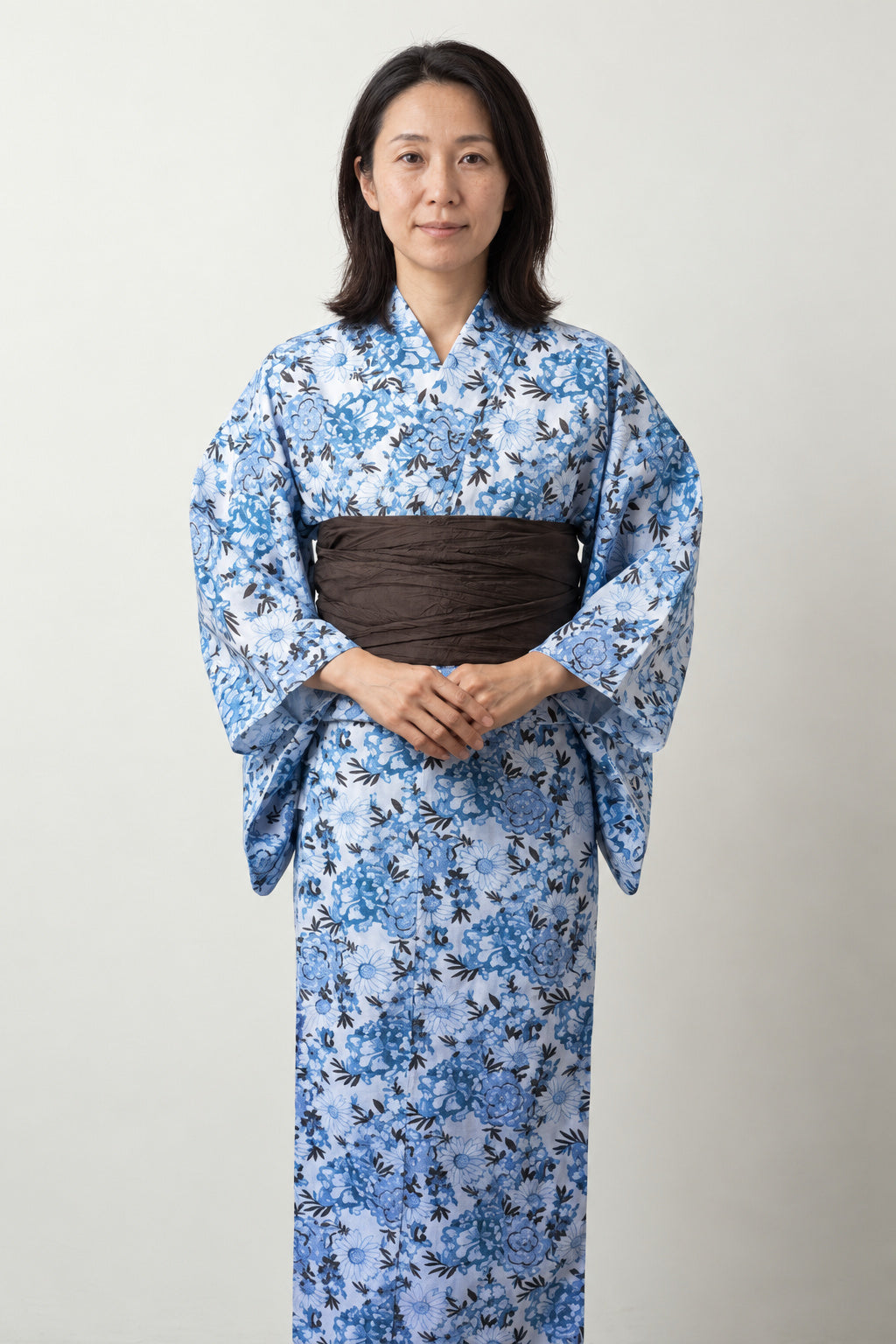 Women's Indigo Floral Yukata 'Aiiro' – pale blue women's yukata with indigo floral print and brown obi belt, traditional Japanese summer kimono, front view on model