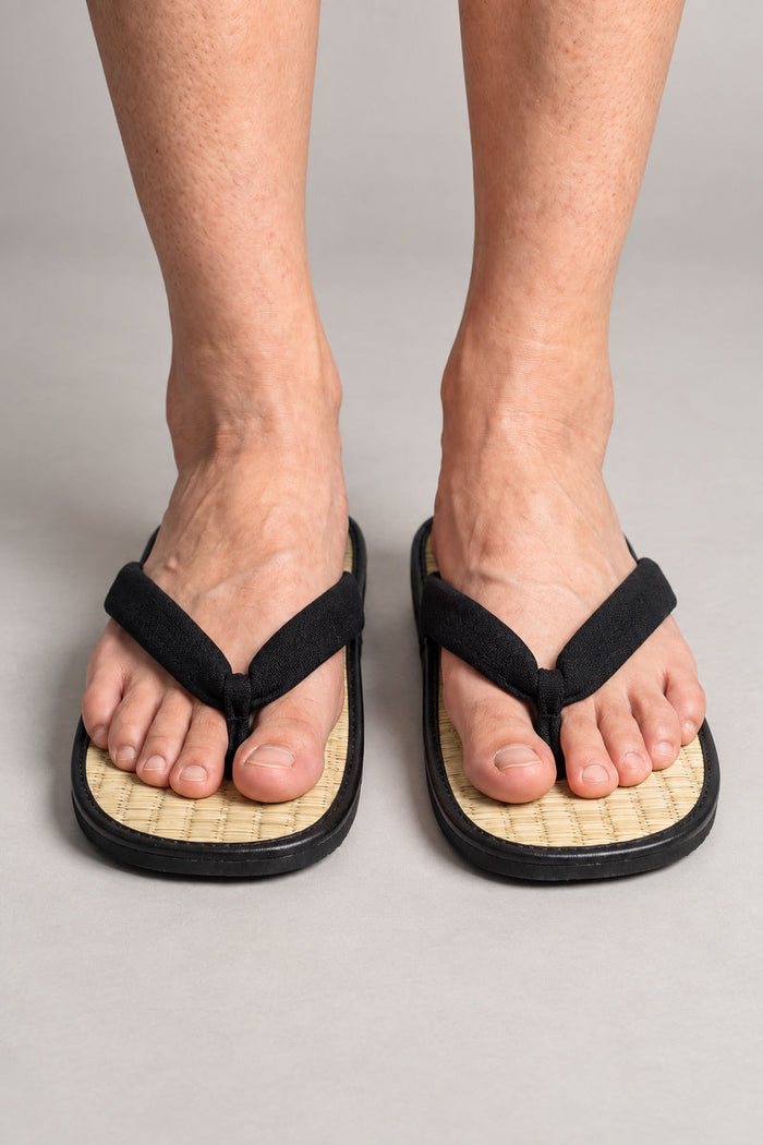 Zori sandals – black zori sandals with woven mat footbed and padded black thong, Japanese flip flops, worn barefoot, front view on model
